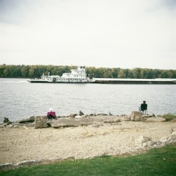 family fishing while a towboat goes up the Mississippi River